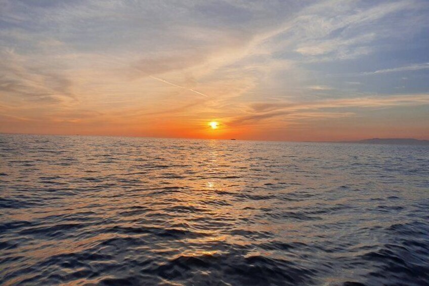 A sunset over a calm sea with a clear horizon. 1