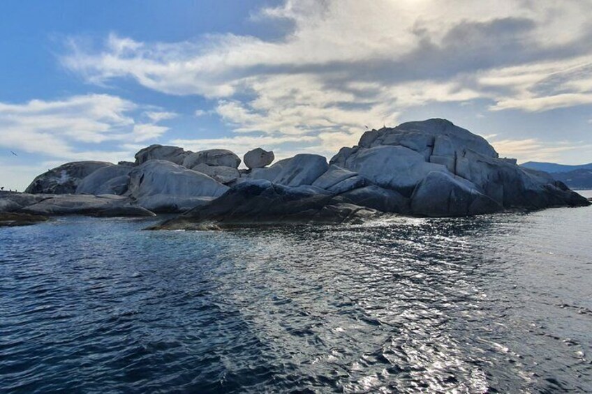 A large rock formation in a body of water with a partly cloudy sky. 5