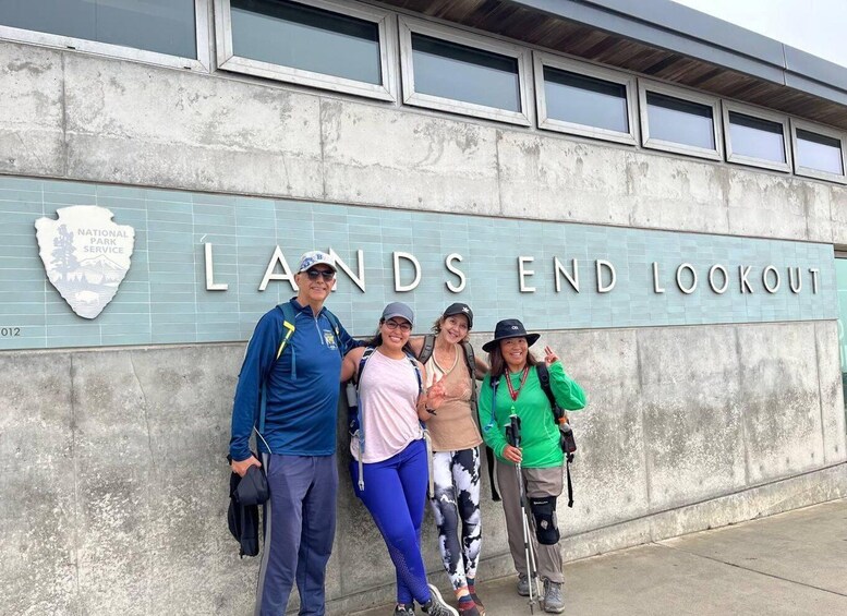 A group of people standing in front of the Lands End Lookout sign. 1
