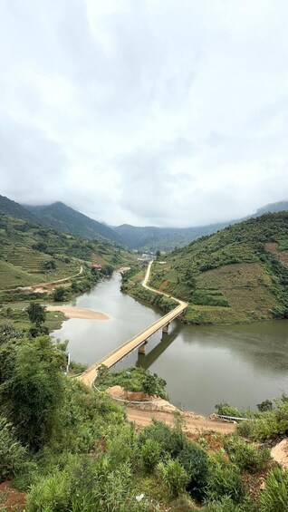 A river with a bridge, surrounded by lush greenery and hills. 2