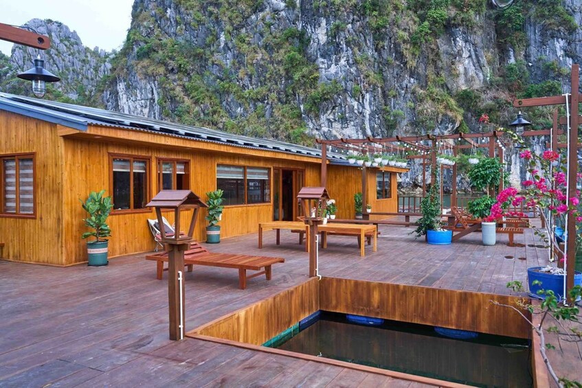 A wooden cabin with a wooden deck, a hot tub, and potted plants. 1