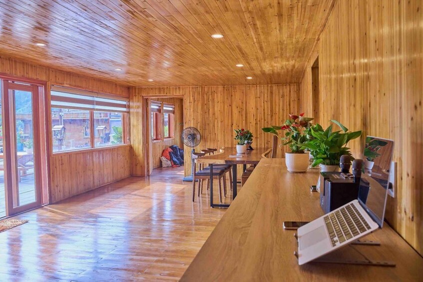 A wooden interior with a laptop on a desk, a fan, and potted plants. 4
