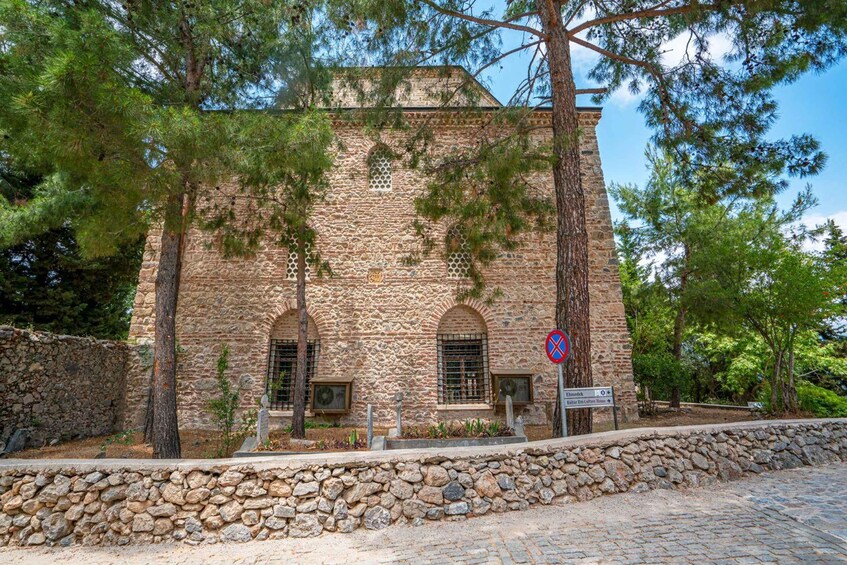 A stone building with arched windows and a stone wall in front. 5