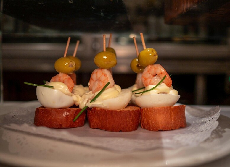 A dish with shrimp, olives, and a creamy topping on bread. 4