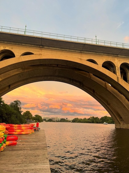A stone bridge with arches over a calm river at sunset. 3