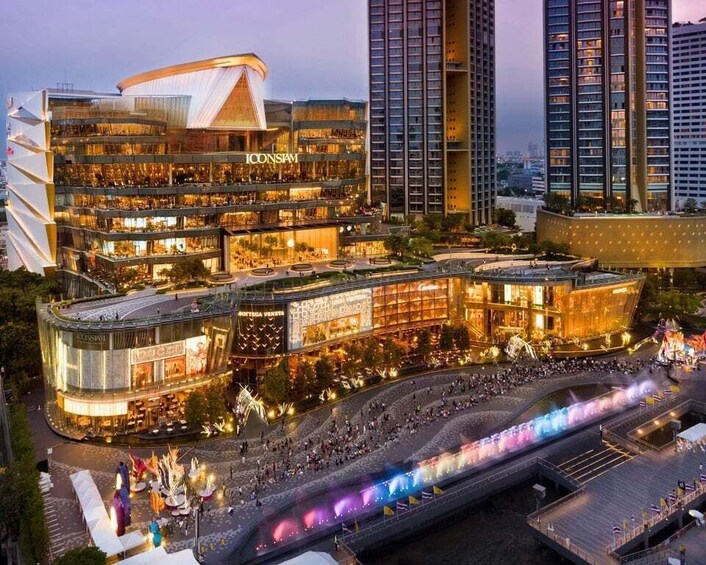 A modern shopping complex with multiple levels and a brightly lit facade, surrounded by high-rise buildings and a busy street with a colorful light display. 5