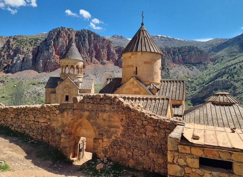 A stone church with a bell tower and a mountain backdrop. 2