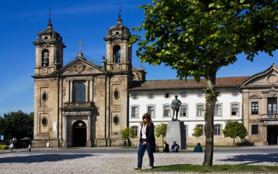 A historic church with two bell towers and a statue in front. 5