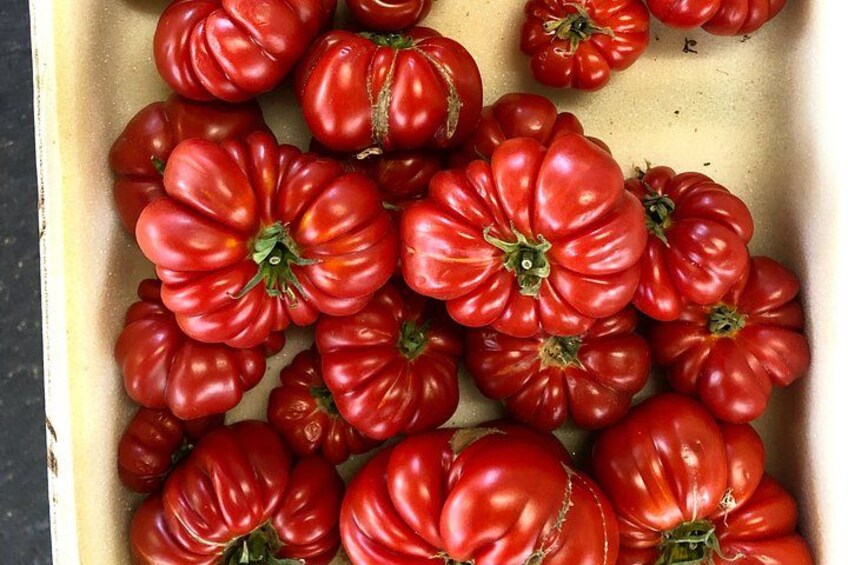 A tray of red tomatoes with green stems. 3