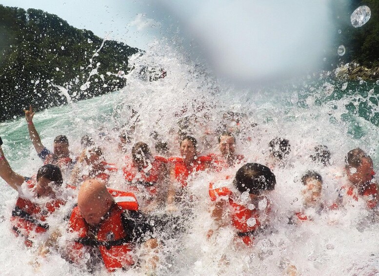 A group of people in a water activity, wearing red life jackets, with a mountainous landscape in the background. 2