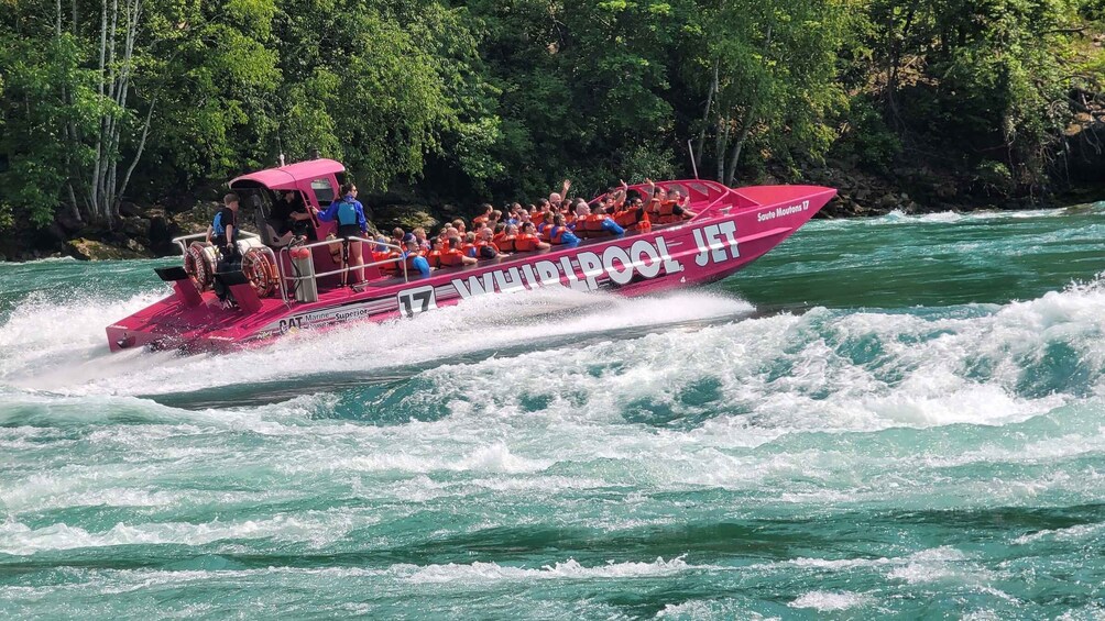A pink boat with the number 17 and 'SAUTE MOUTONS 17' written on it, moving through turquoise water. 4