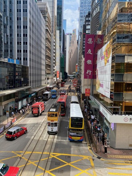 A busy urban street with trams, buses, and cars, surrounded by high-rise buildings and commercial signage. 5
