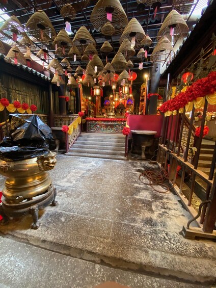 A temple interior with traditional Chinese architecture, featuring a central altar, red and gold decorations, and hanging paper lanterns. 3
