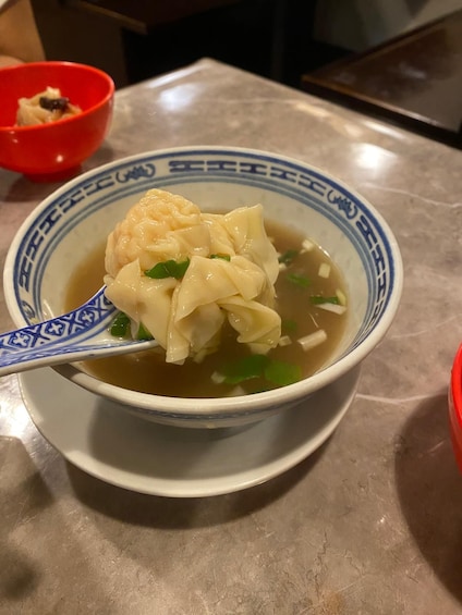 A bowl of soup with dumplings and green onions. 3