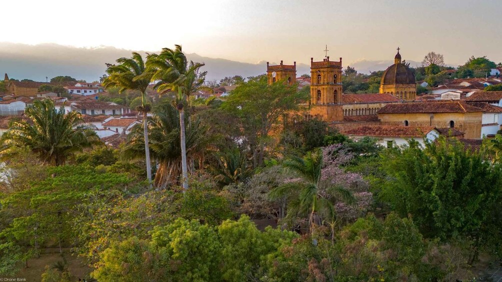 A coastal town with a prominent church, palm trees, and a mountainous backdrop. 2