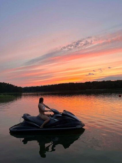 A person on a jet ski on a calm lake during sunset. 3