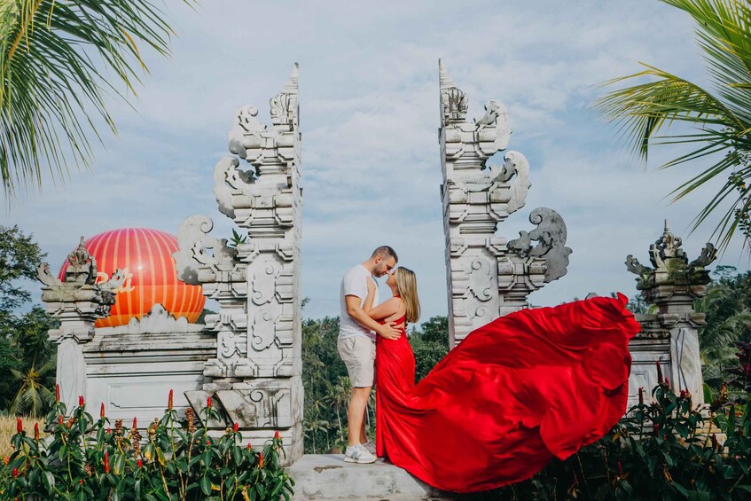 A couple embracing in front of a temple with ornate carvings and a red umbrella. 2