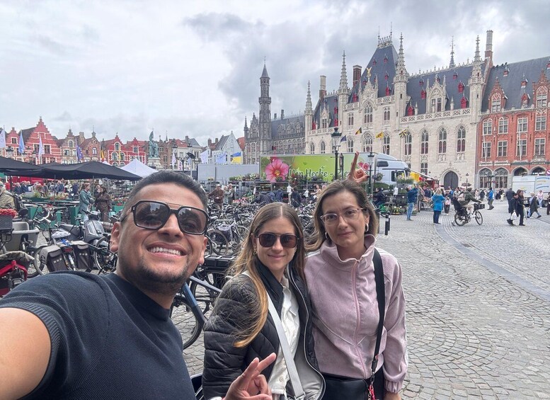 A cobblestone square with historic buildings, a market, and people. 4