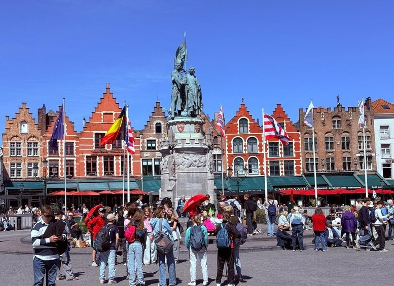 A bustling square with a central statue, surrounded by historic buildings and flags. 1