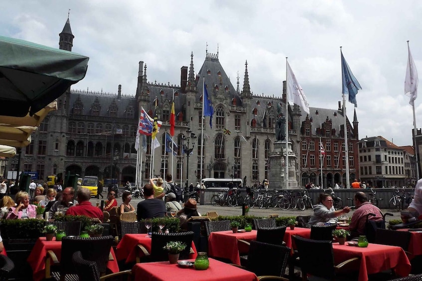 A historic building with flags, outdoor seating, and a busy street scene. 1