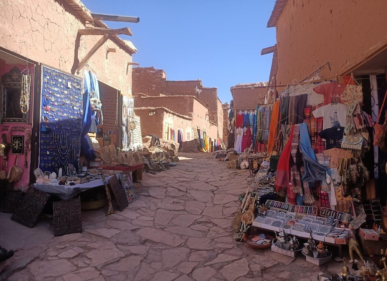 A narrow street with shops selling jewelry, textiles, and pottery. 3