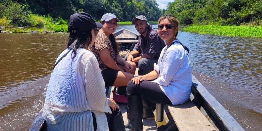 A group of people on a narrow boat on a river surrounded by greenery. 4