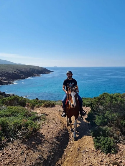 A person riding a horse on a dirt path with a coastal landscape in the background. 4
