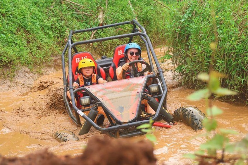 A vehicle navigating through a muddy terrain with vegetation on the sides. 1