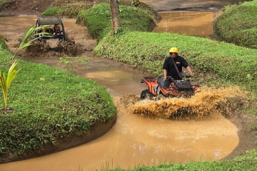 A person on an ATV navigating a muddy water channel. 2