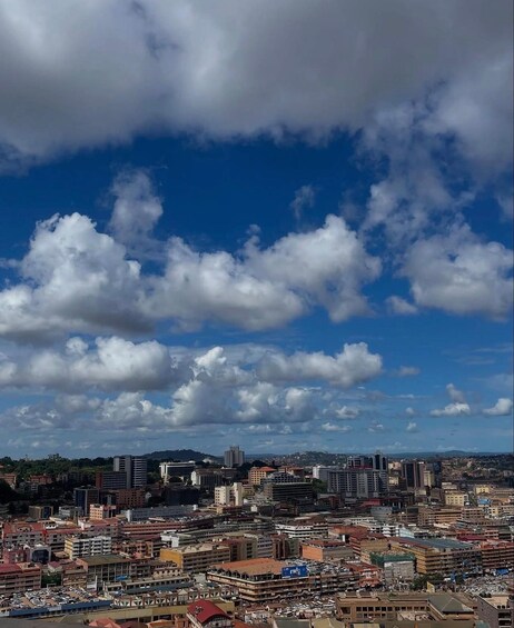 A cityscape with a variety of buildings, including high-rises and smaller structures, under a partly cloudy sky. 1