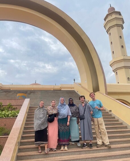 A group of people standing on a staircase with a large arch structure and a minaret in the background. 4