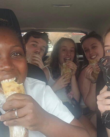 A group of people inside a vehicle, some holding food. 3