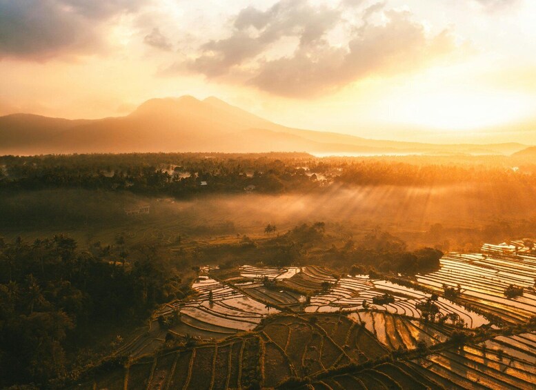Des rizières en terrasses, une chaîne de montagnes et un lever ou un coucher de soleil. 4
