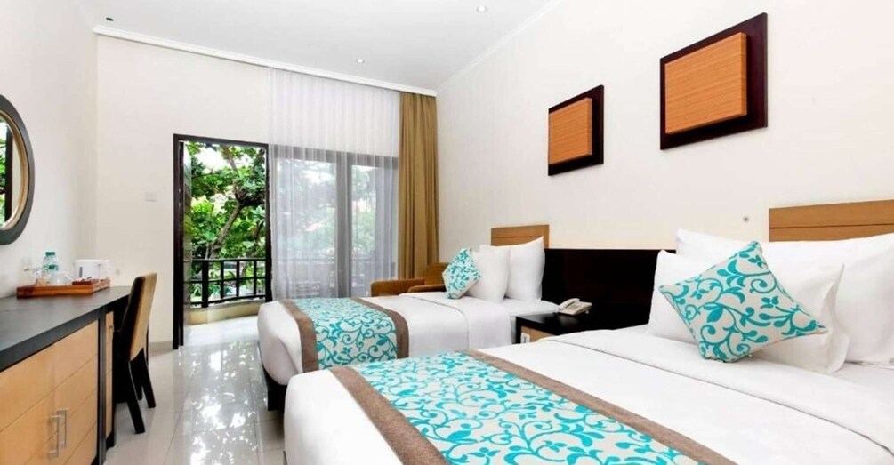 Une chambre d’hôtel avec deux lits, un bureau et une vue sur la verdure environnante. 3