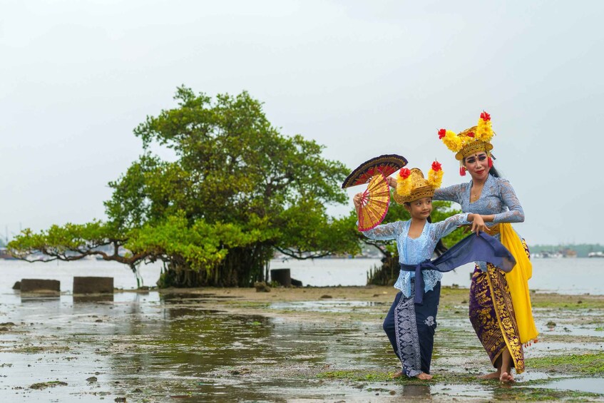 Deux personnes vêtues de costumes traditionnels, près d’une étendue d’eau, avec des arbres en arrière-plan. 2