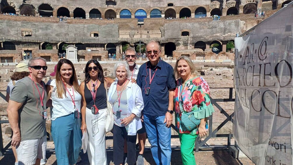 A group of people standing in front of an ancient amphitheater with multiple arches. 3