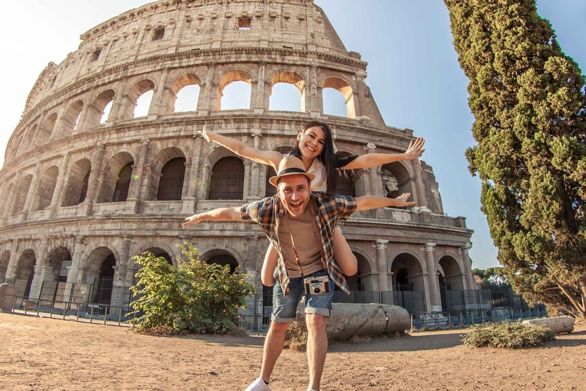 A person carrying another on their shoulders in front of the Colosseum. 4