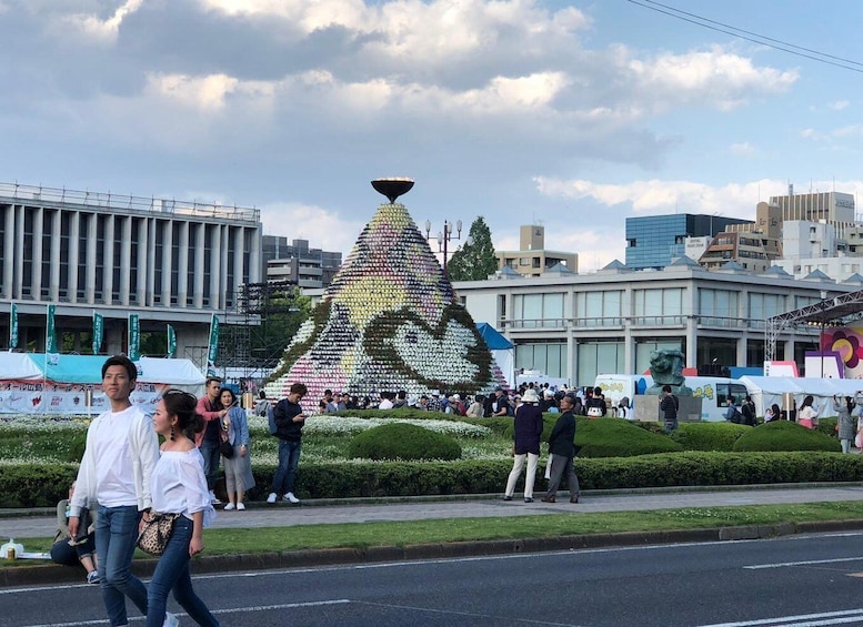 A crowd gathered around a large, colorful sculpture in an urban setting. 3