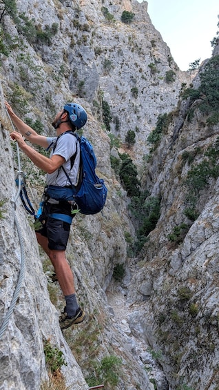 A person rock climbing a steep, rocky cliff with a blue helmet and harness. 1