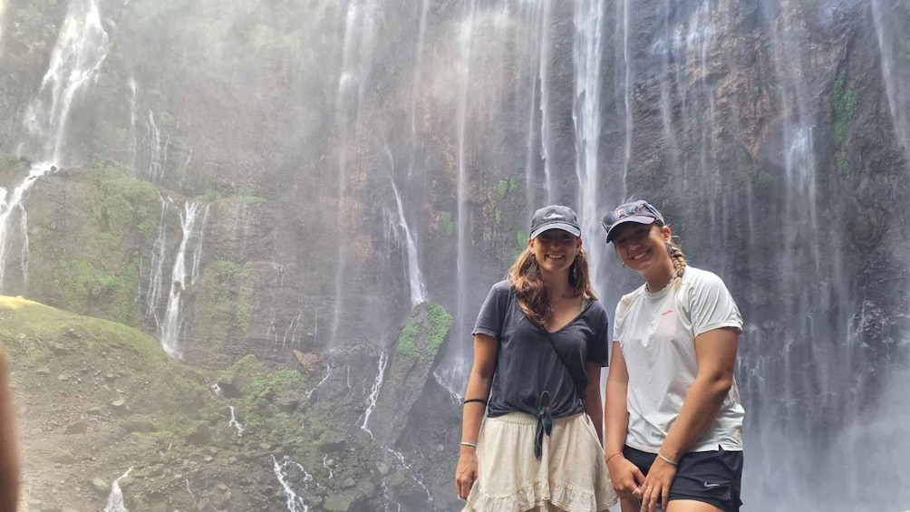 Two people standing in front of a waterfall. 5