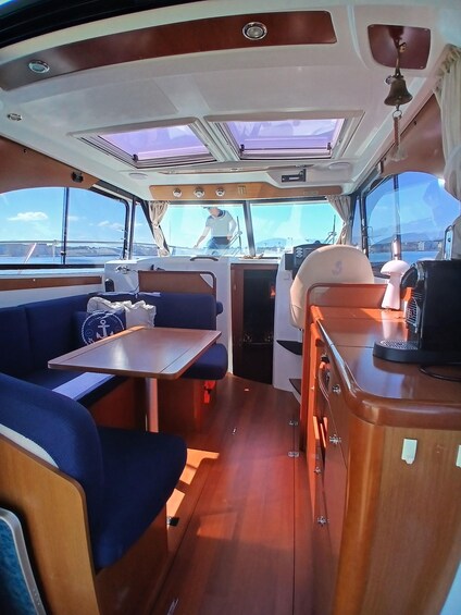 A boat interior with a dining area, seating, and a view of the water. 5