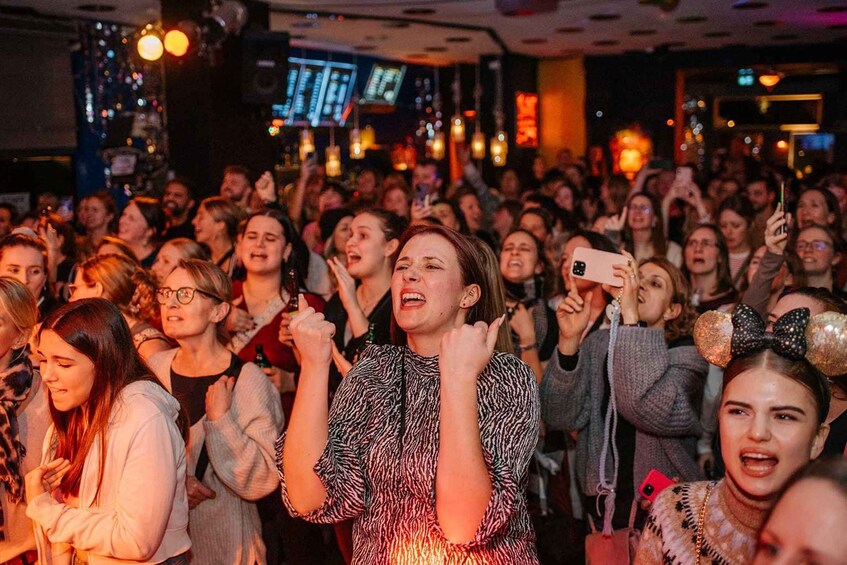 A crowded indoor event with people holding up their phones, likely taking photos or videos. 5