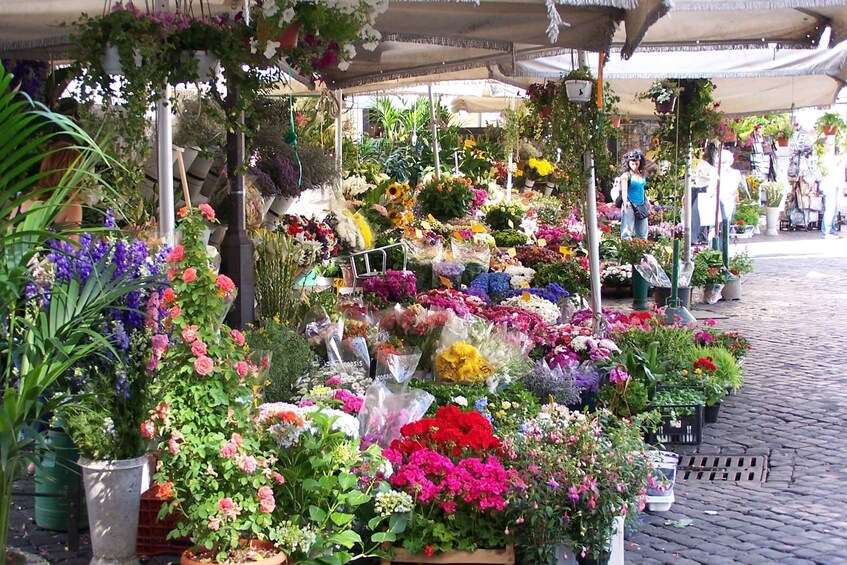 A flower market with various plants and flowers displayed in pots and baskets. 1