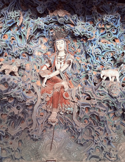 A detailed sculpture with a seated figure, intricate patterns, and two animal figures. 3