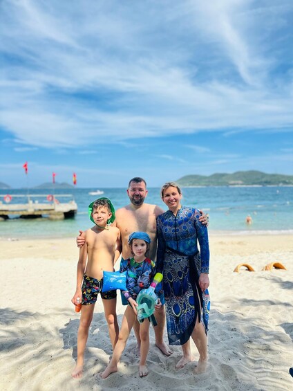 A family on a sandy beach with a clear sky and calm sea. 4