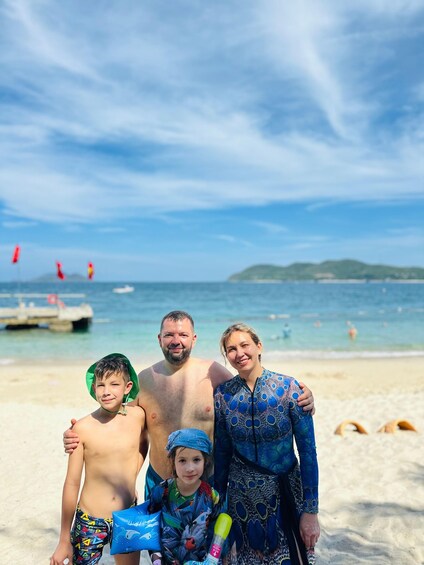 A family on a beach with a pier and boats in the background. 5