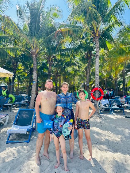 A family on a sandy beach with palm trees and beach chairs. 3