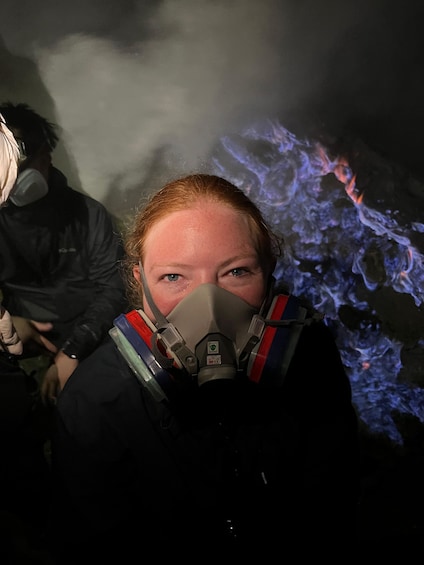 A person wearing a gas mask with a blue flame-like background. 1