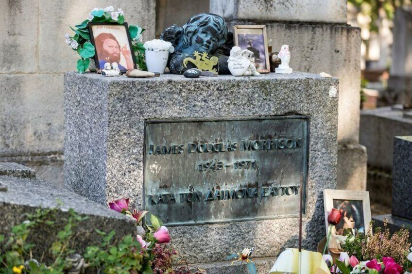 A gravestone with a name and dates, surrounded by flowers and personal items. 2