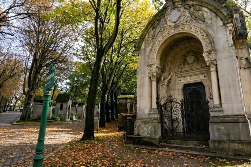 A stone archway with 'FAMILLE J.P. CAI' inscribed, surrounded by trees and a cobblestone path. 4